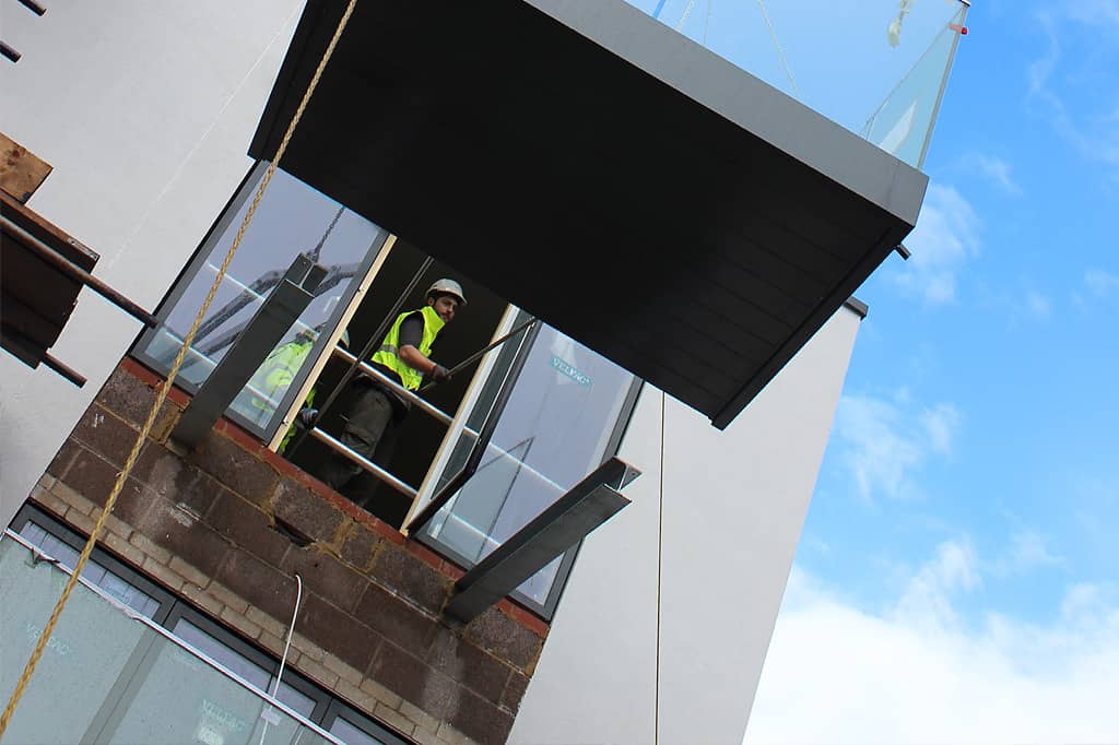 Glide-On balconies on UK construction site. Worker indoors.