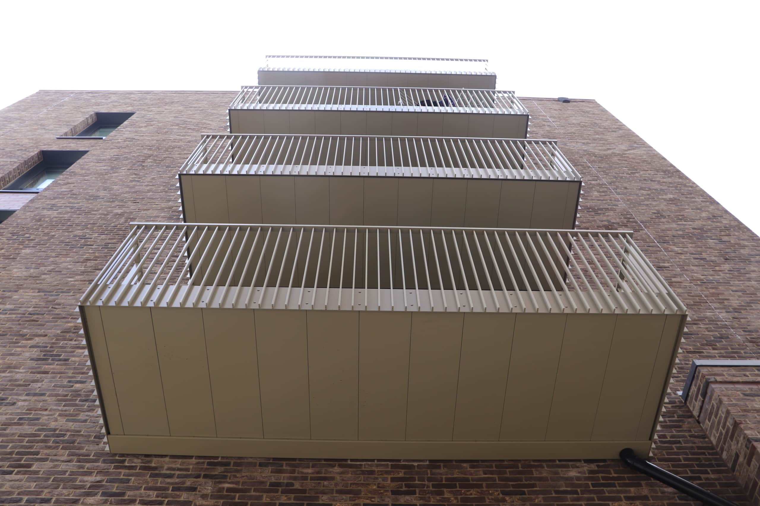 Stack of balconies with vertical bar balconies and gold soffit drainage in Park Royal, London